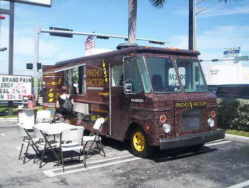 Photo colorée d’un food truck à Miami servant un sandwich cubain avec des garnitures fraîches, représentant la diversité de la street food locale.
