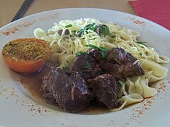 Civet de sanglier corse servi dans une assiette en terre cuite avec des herbes du maquis