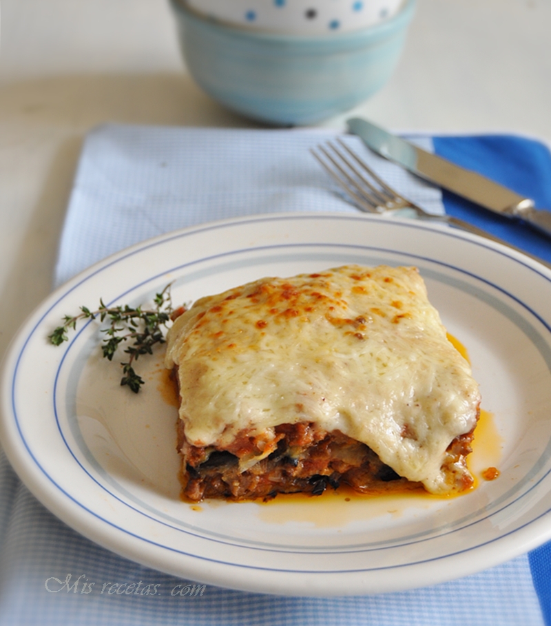 Portion de moussaka grecque servie dans une assiette blanche avec des herbes fraîches