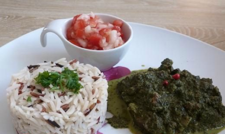 Plat traditionnel malgache romazava servi avec du riz blanc et des légumes verts dans une assiette rustique.
