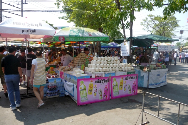 Marché de street food animé avec divers stands proposant des spécialités culinaires locales, visiteurs dégustant des plats typiques dans une ambiance festive.