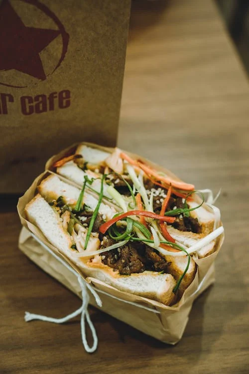 Sandwich bánh mì vietnamien garni de légumes et de viande sur une planche en bois
