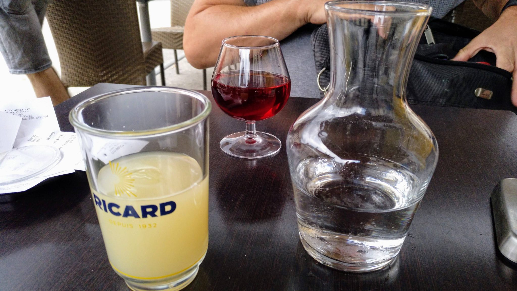 Verres de vin, pastis et cidre servis sur une table traditionnelle française en extérieur.