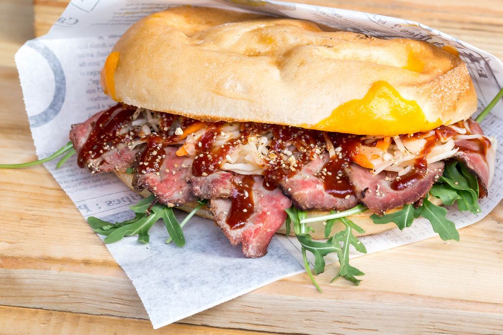 Sandwich gourmand au magret de canard fumé, sauce chutney, spécialité street food française.